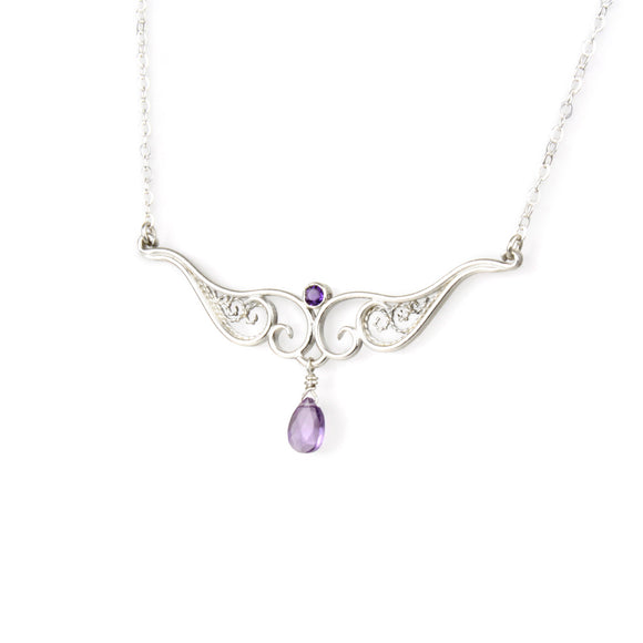 A graceful silver necklace with delicate filigree wirework, accented with purple amethyst, on a white background.