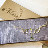 A graceful silver necklace with delicate filigree wirework, accented with green peridot, in a gift box.